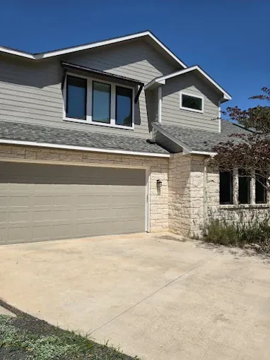 Stone-and-siding Pflugerville home exterior with clean paintwork and a freshly finished garage door